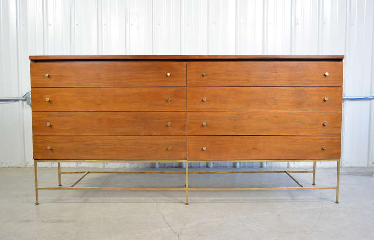 An eight drawer dresser in walnut by Paul McCobb for Calvin.  Labeled.  Beautiful brass legs and stretchers form the base for this piece.  Brass hardware.  Newly refinished.