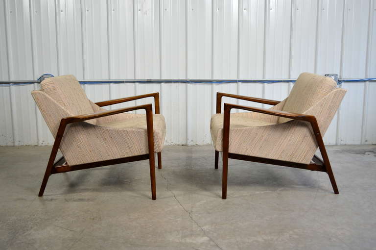 A pair of lounge chairs by Ib Kofod-Larsen.  Sculptural walnut frames.  In excellent original condition.