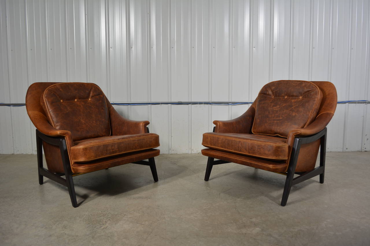 A pair of stunning leather lounge chairs designed by Edward Wormley for Dunbar. Down filled back cushion. External, solid wood frames in a dark mahogany stain. Both chairs retain the original Dunbar decking. Newly restored.