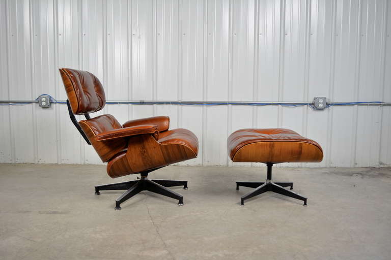 Lounge chair and ottoman in rosewood designed by Charles & Ray Eames for Herman Miller. Nicely grained rosewood frame has been refinished. New cushions covered in a cognac leather by Moore & Giles. Leather samples available upon request. Labeled.