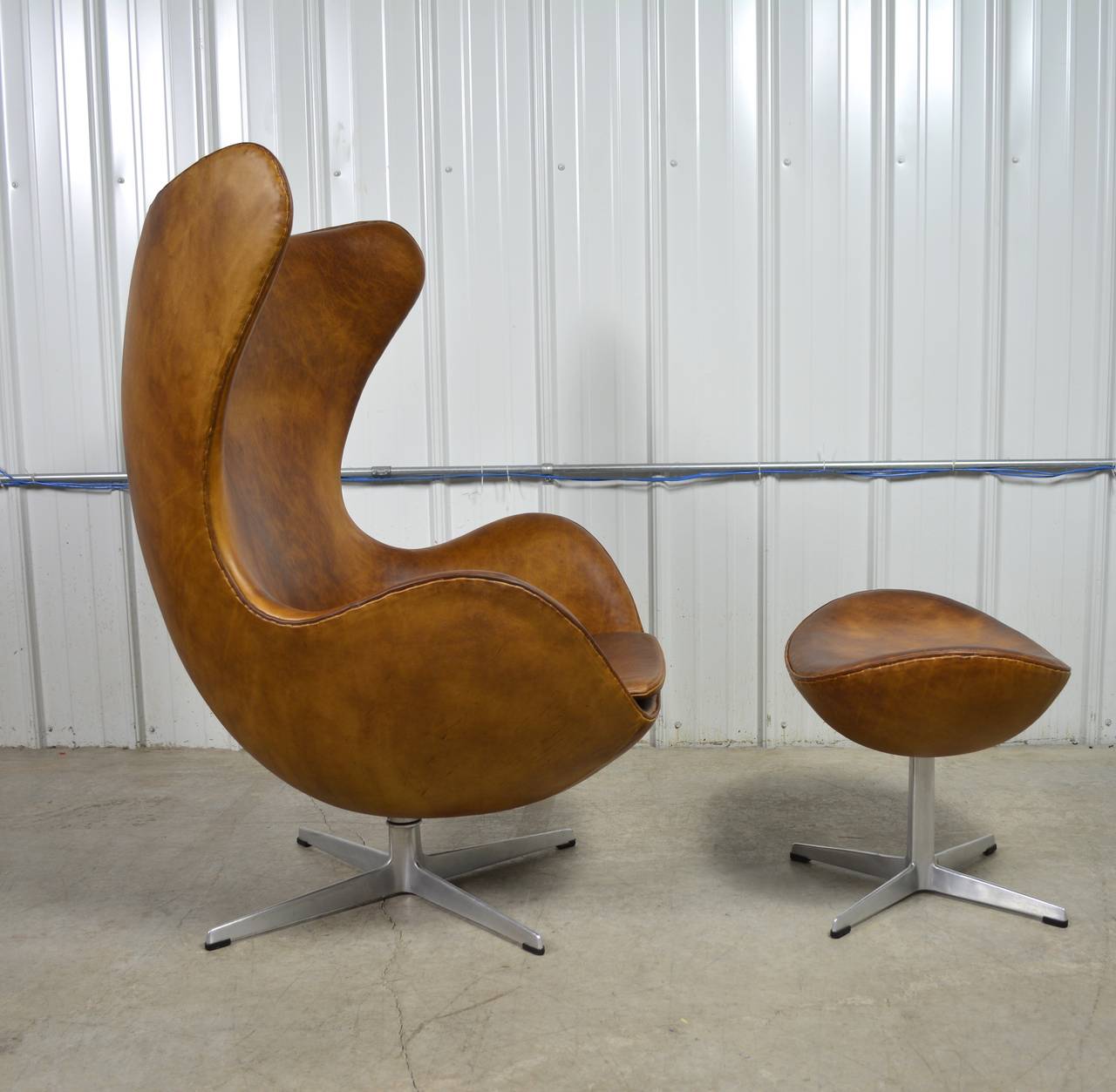 Egg chair and ottoman designed by Arne Jacobsen. This set dates to 1966. Tan leather upholstery shows great character. Both pieces are labeled.