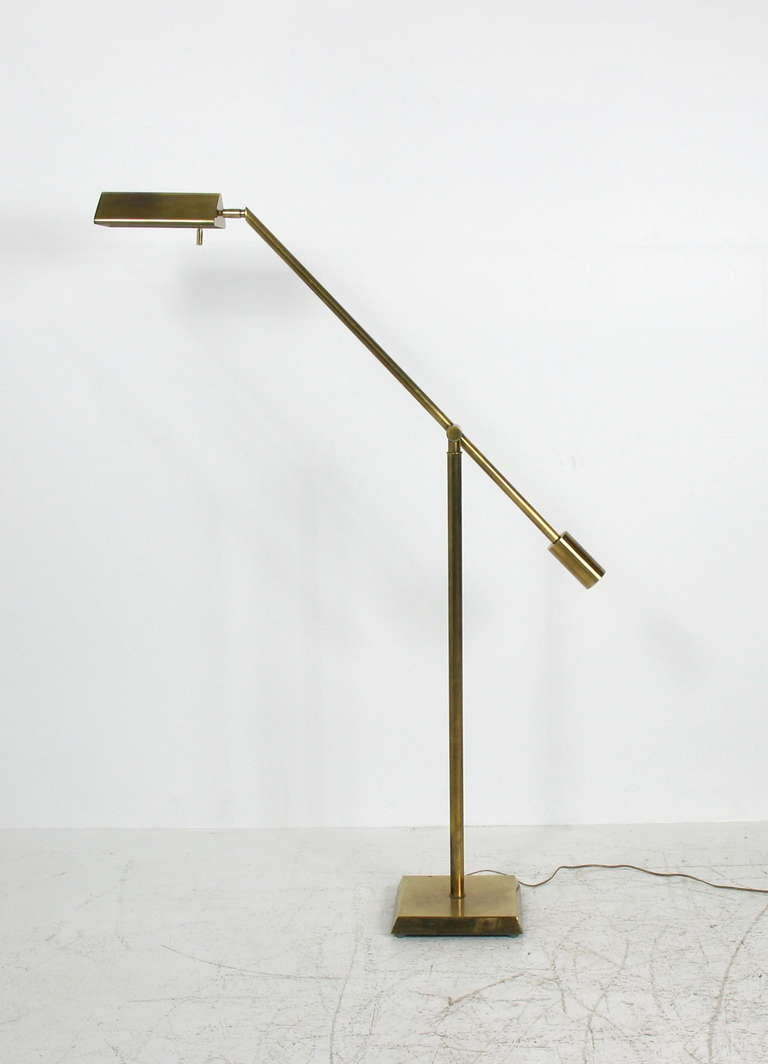 An adjustable brass floor lamp by Chapman.  A single counter balanced arm.  Sits on a square beveled base.  Brass shows a nicely aged patina.