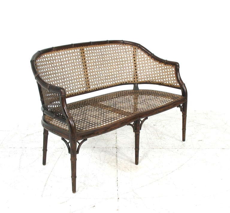 A mid-20th century faux bamboo settee/bench.  Caned back and seat.  Tufted seat cushion