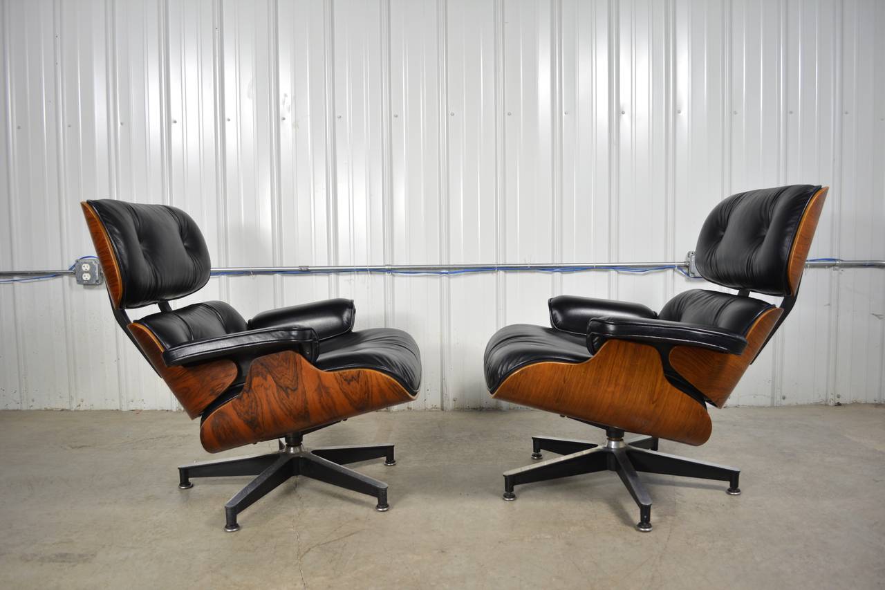 A beautiful pair of early Eames 670/671 lounge chairs and ottomans in Rosewood. Matching black leather upholstery. Both sets are labeled.