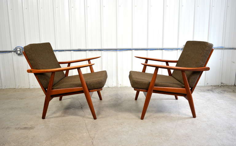 A pair of GE-270 teak lounge chairs designed by Hans Wegner for Getama.  The teak frames have a deep, rich color.  The custom brass hardware shows a nicely aged patina.  The cushions retain the original Halingdal Kvadrat wool fabric.  Both chairs