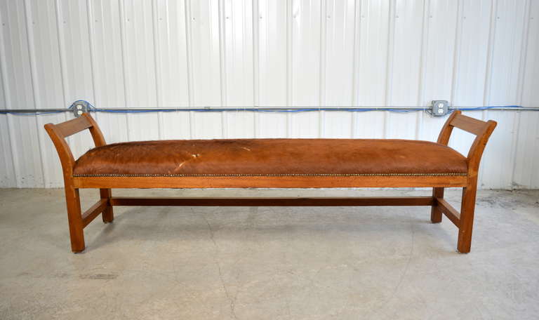 A 7' long bench.  Solid wood frame.  Seat upholstered in cowhide with nail head trim.