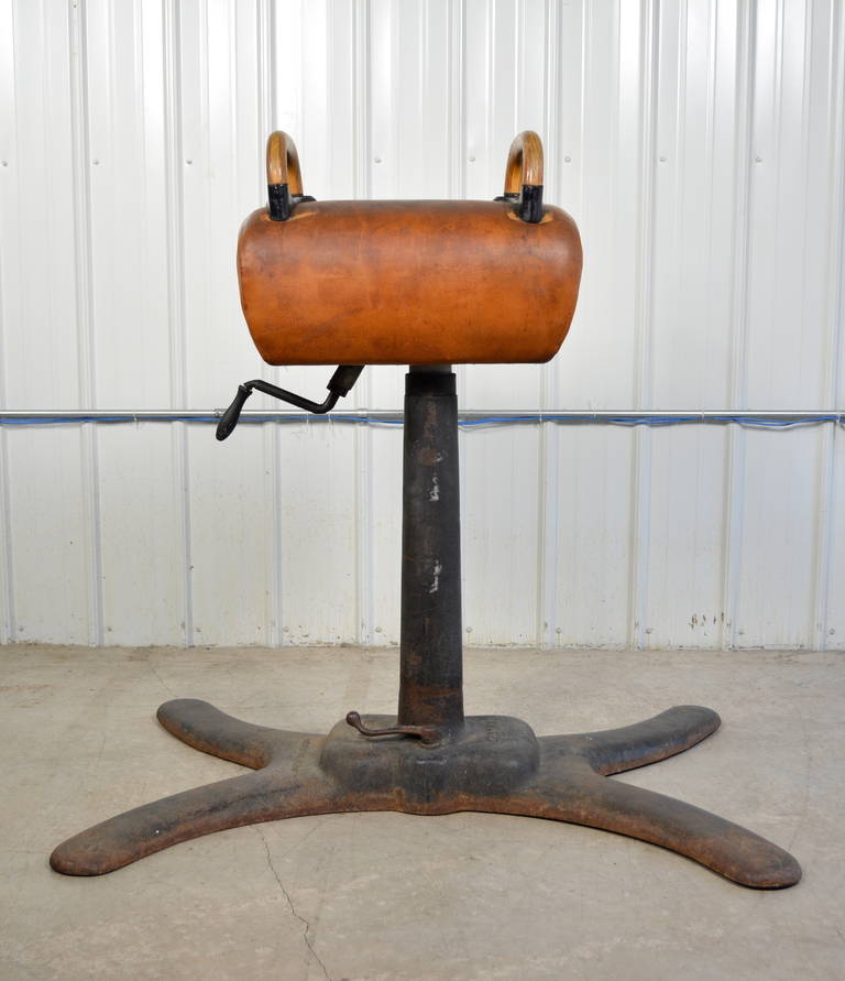 A gymnastics pommel horse produced in 1913 by Medart in St. Louis.  Original leather.  Oak handles.  Medart label on both ends and on cast iron base.  Handle on base raises on to castors.  The pommel itself is height adjustable.