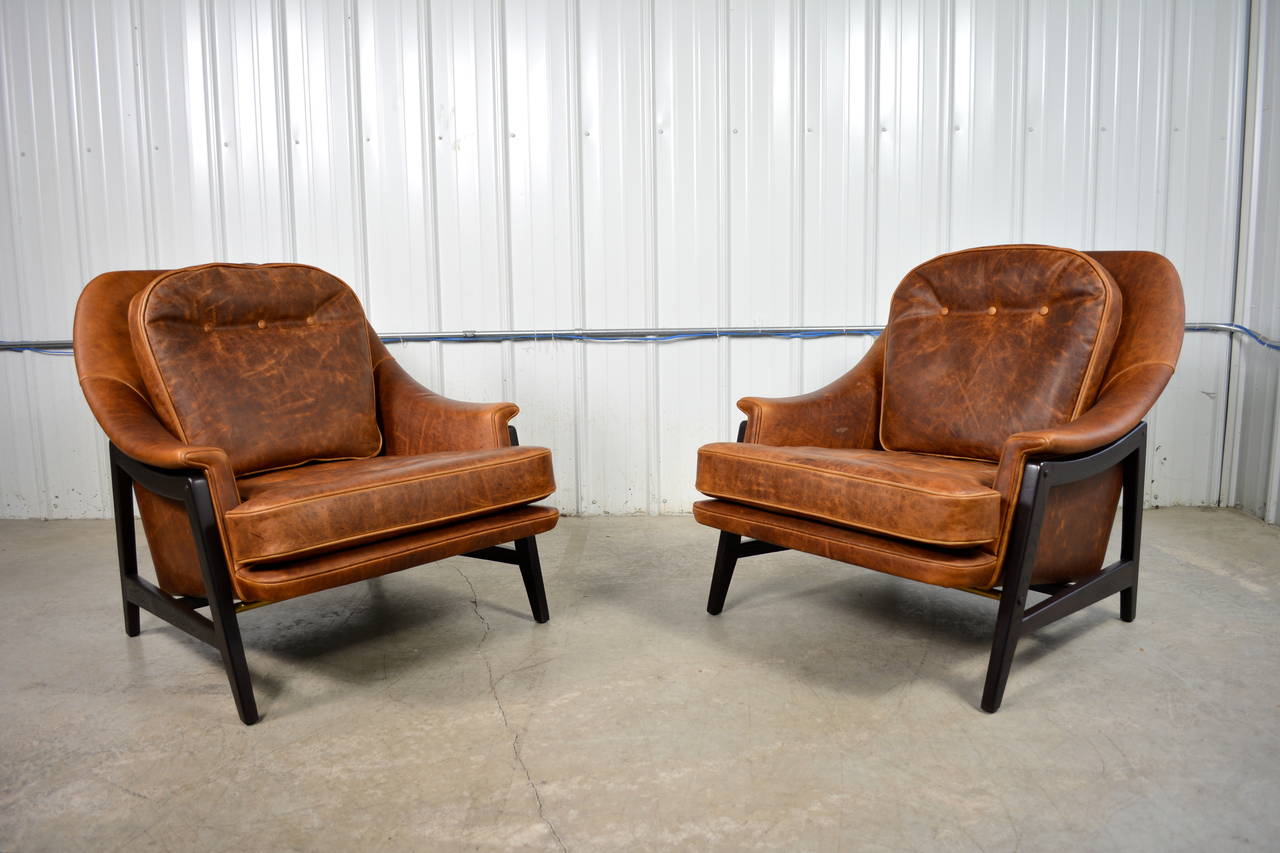 A pair of stunning leather lounge chairs designed by Edward Wormley for Dunbar.  Down filled back cushion.  External, solid wood frames in a dark mahogany stain.  Both chairs retain the original Dunbar decking.