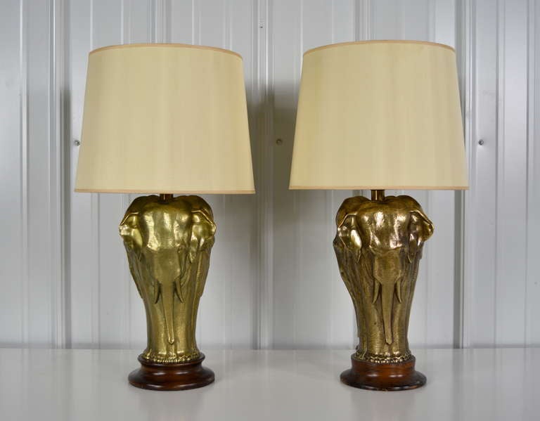 A pair of sophisticated brass lamps in the form of three elephants.  Each on a round wood base.