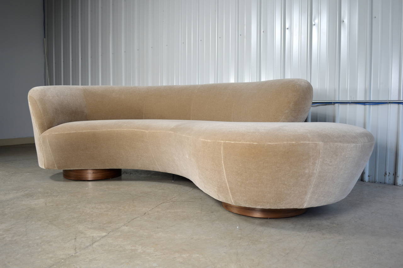 A serpentine sofa designed by Vladimir Kagan for Directional. Circular walnut plinth bases. Newly recovered in mohair. Lucite support plate. Directional label. A matching sofa with arm at the opposite end is available.