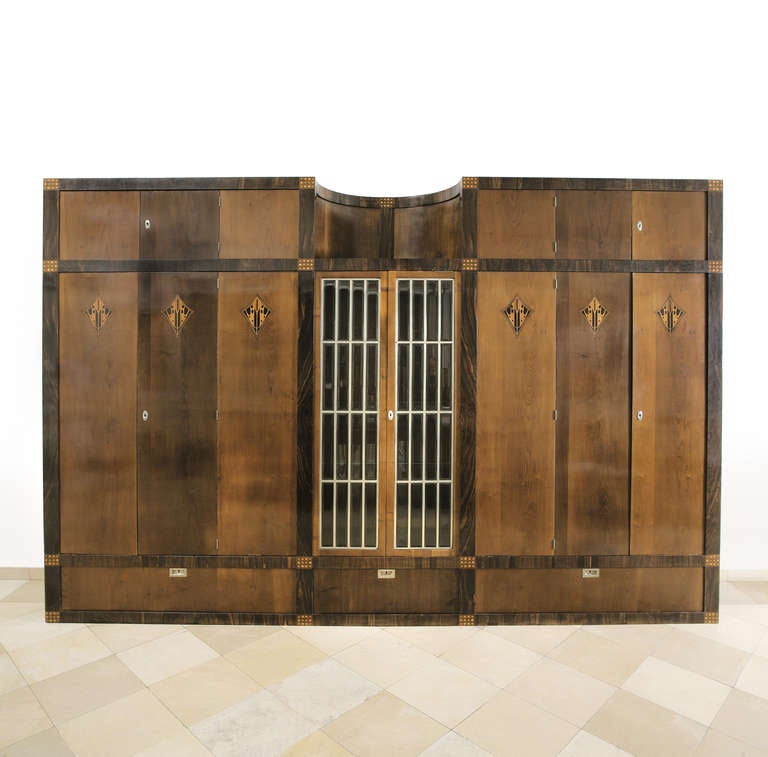 Soft-wood corpus, veneered with exotic woods, inlays of different woods, inside veneered with maple, alpaca fittings and rods, the centrepiece with bossed cut glass doors.
Original condition, professionally restaured, some pieces of the inlay were