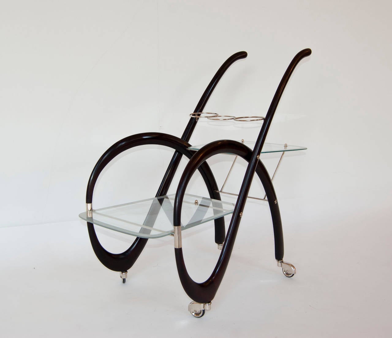 Very particular shaped serving cart with two glass levels and three bottle holders in the upper part. The dark patinated wood goes very well with the silver plated brass and the fine glass.