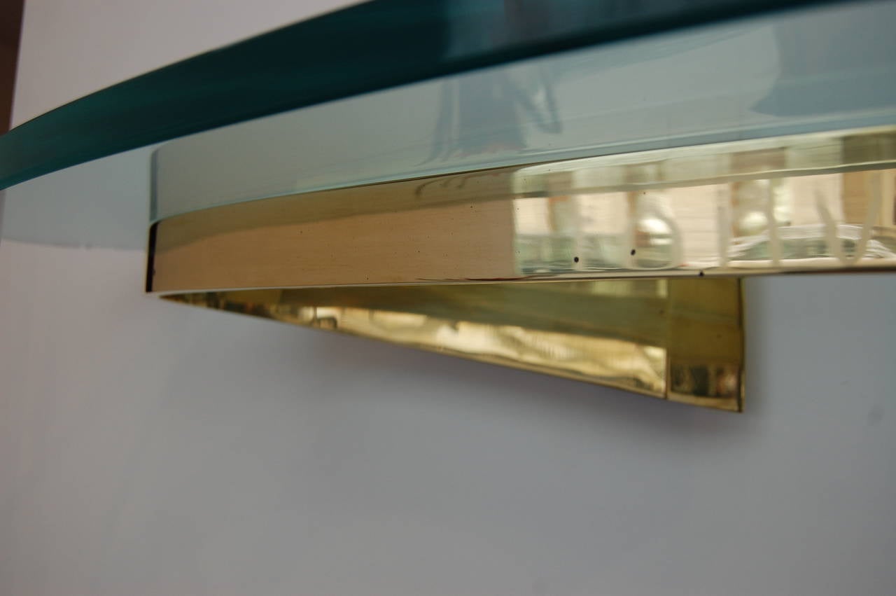 Wall-mounted elliptical brass support with light turquoise original glass top. This very simple but highly impressive design is typical for the extraordinary quality of Fontana Arte design products. 

Illustrated as:
Modell 2186 in Illuminatione
