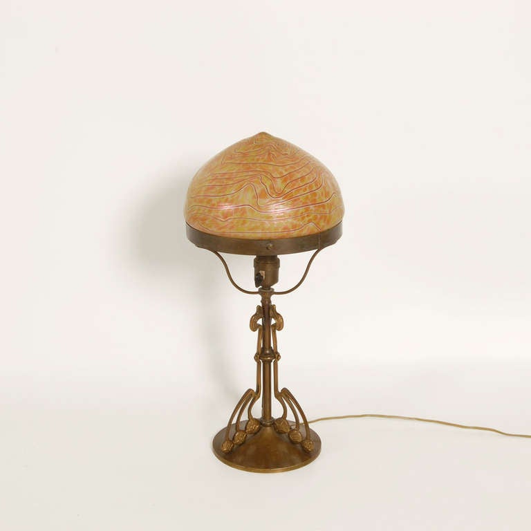 A cast bronze table lamp designed by Gustav Gurschner in 1905. The Austrian born sculptor was influenced by the flowing lines of Art Nouveau and the symmetry of the Wiener Werkstätte. The glass shade is attributed to Loetz, who was the premier
