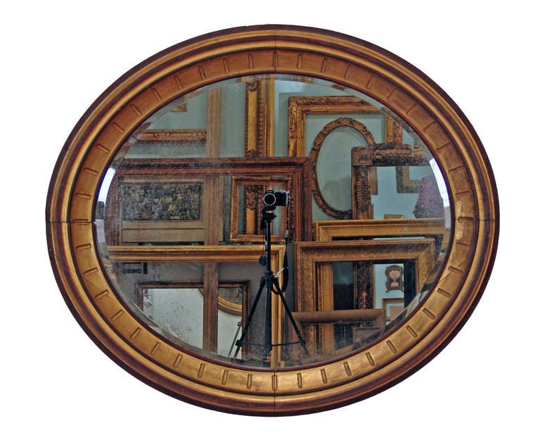 PERIOD FRAME c. 1860s American oval gilded wood frame with radial notched panel. Original gilding and patina. Price includes medium-antiqued beveled mirror already installed. Can hang vertically or horizontally. Measurements are given for vertical