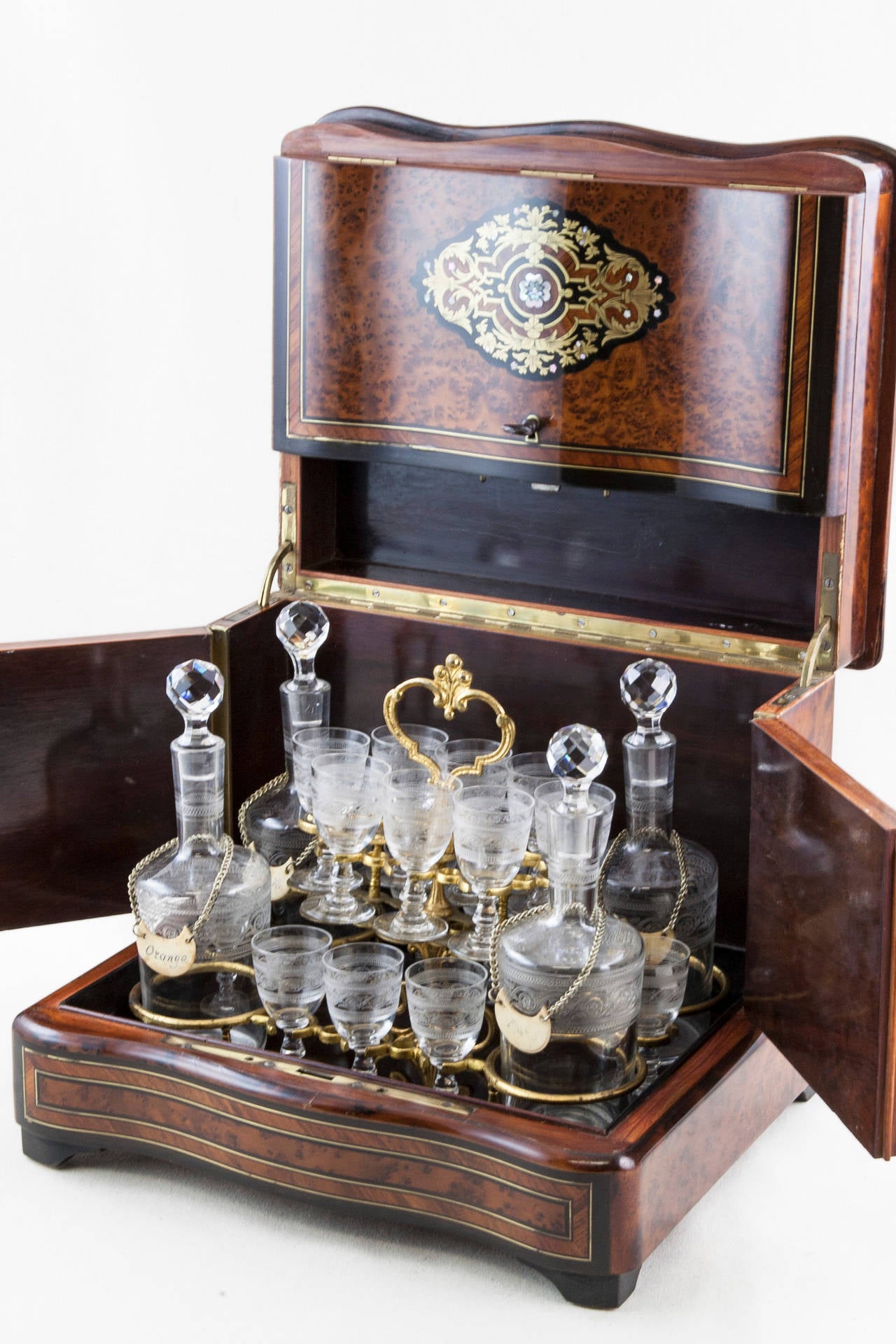 This century 1860 Napoleon III marquetry cave à liqueurs or liqueur box has exotic wood, gilt bronze and mother-of-pearl inlay. The interior includes a complete cordial service with four etched crystal carafes and 16 glasses, ten etched with a