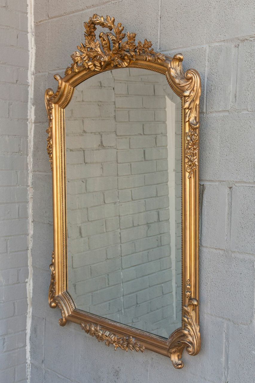 This elegant Louis XV style giltwood mirror features a crown of Laurel with cascading bows and flowers.  The beveled mirror follows the beautifully scalloped shape.  c. 1890