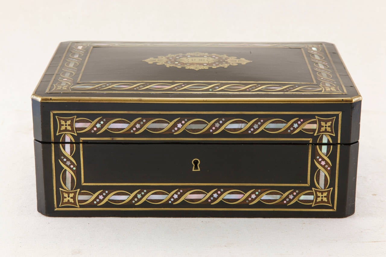 This exquisite Napoleon III box is ebonized and inlaid with mother-of-pearl and bronze. The natural wood tone of the mahogany is used as a mid-tone against the black lacquer and pearl to create a trompe l'oeil effect. A substantially sized box with