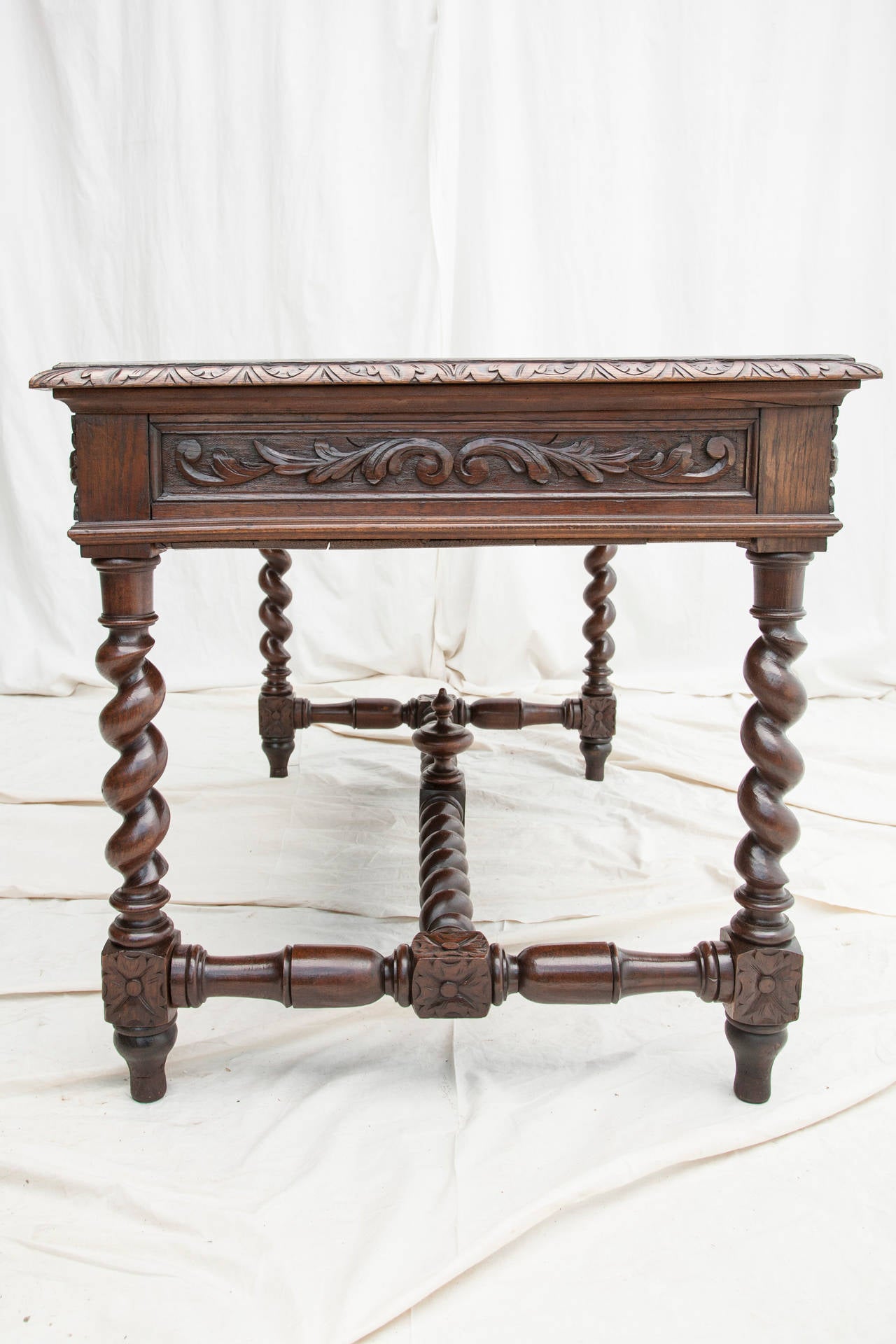 An exquisite example of the Louis XIII style, this hand carved oak desk features barley twist legs, gargoyle pulls, and elaborate scrolling leaf work on all sides. Three functioning drawers on one side and three false drawers on the opposite side