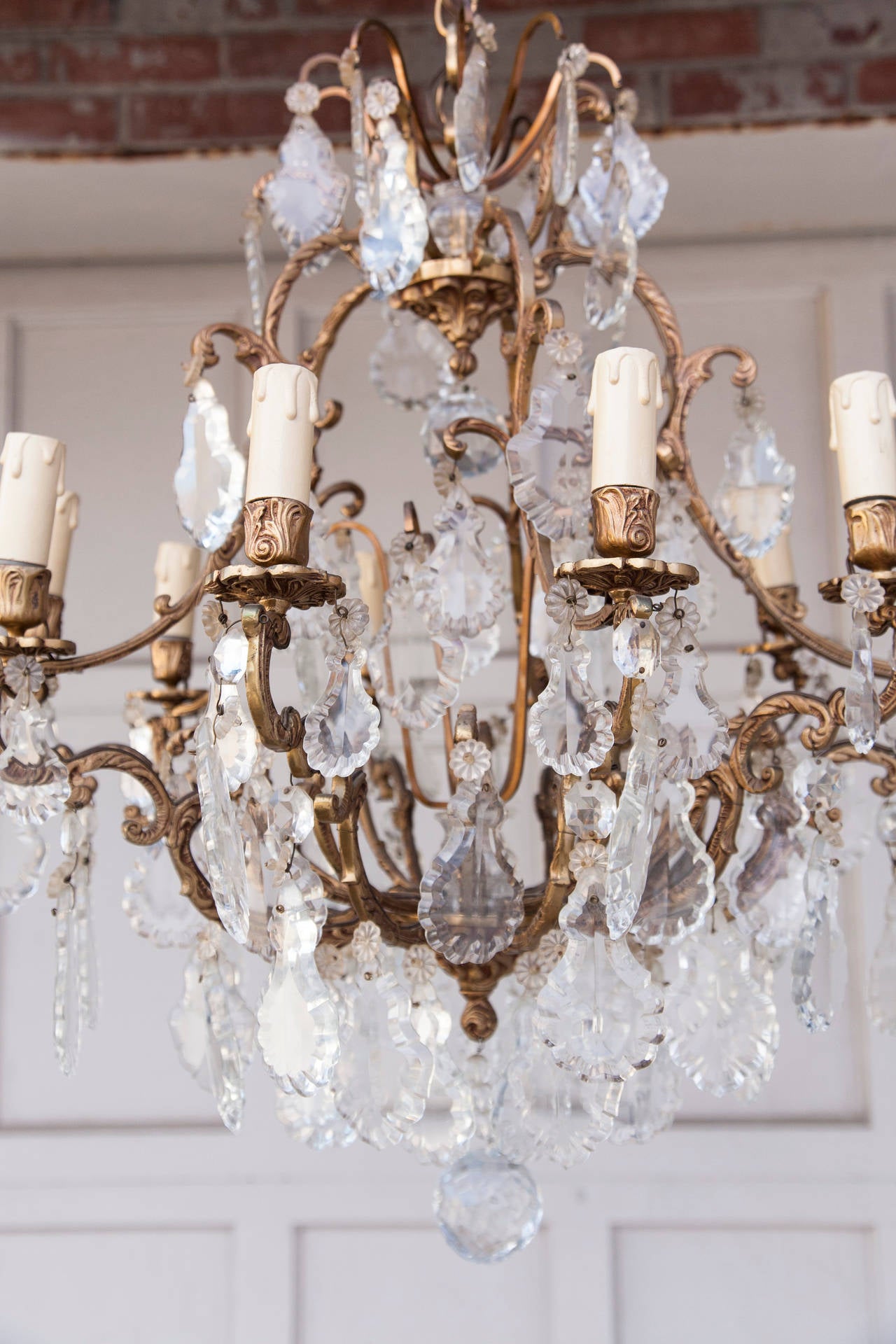 This crystal and bronze ten light chandelier has an elegant bronze cage style frame with hand-cut and polished pendalogue and rosette drops. All of the bronze is of intricately worked Louis XV motifs of scrolling flora.  The density of the crystals