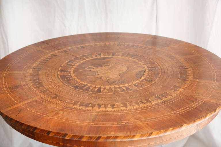 This exceptional burled walnut and lemon wood Italian marquetry gueridon or entry table features an inlaid knight on horseback in a sunburst pattern, c. 1850. With inlaid arrow point detail continuing down the pedestal base the refined details on