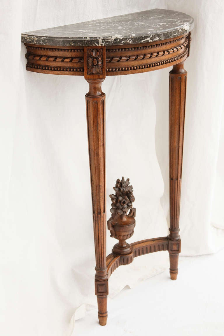 This nineteenth century petite console of richly toned walnut features an ornately carved urn with a bouquet of roses. The original Saint Anne marble top in a deep grey tone will blend well with all palettes. A great scale for a small entry or hall.