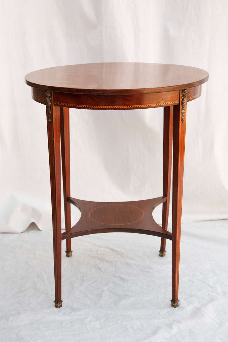 A beautiful blend of Art Deco and Louis XVI elements, this early twentieth century rosewood and mahogany marquetry table features delicate and refined details.  With a handsome cubic patterned inlaid top, bronze ormolu, and delicately tapered legs