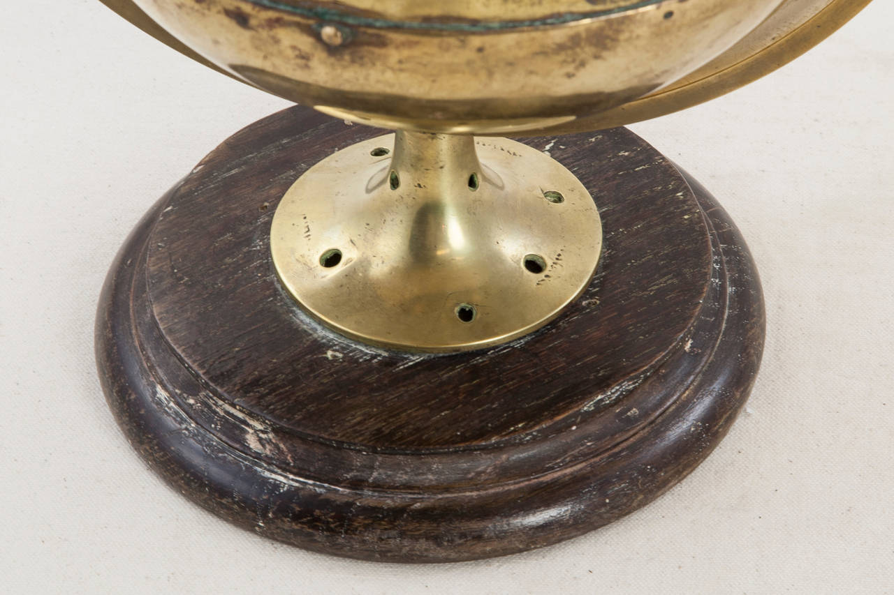 This large brass nautical compass was custom made in France around the year 1900 and features a central dial decorated with a fleur de lys to indicate North. The dial is suspended in water, pivoting to remain level on a circular suspension.  Mounted