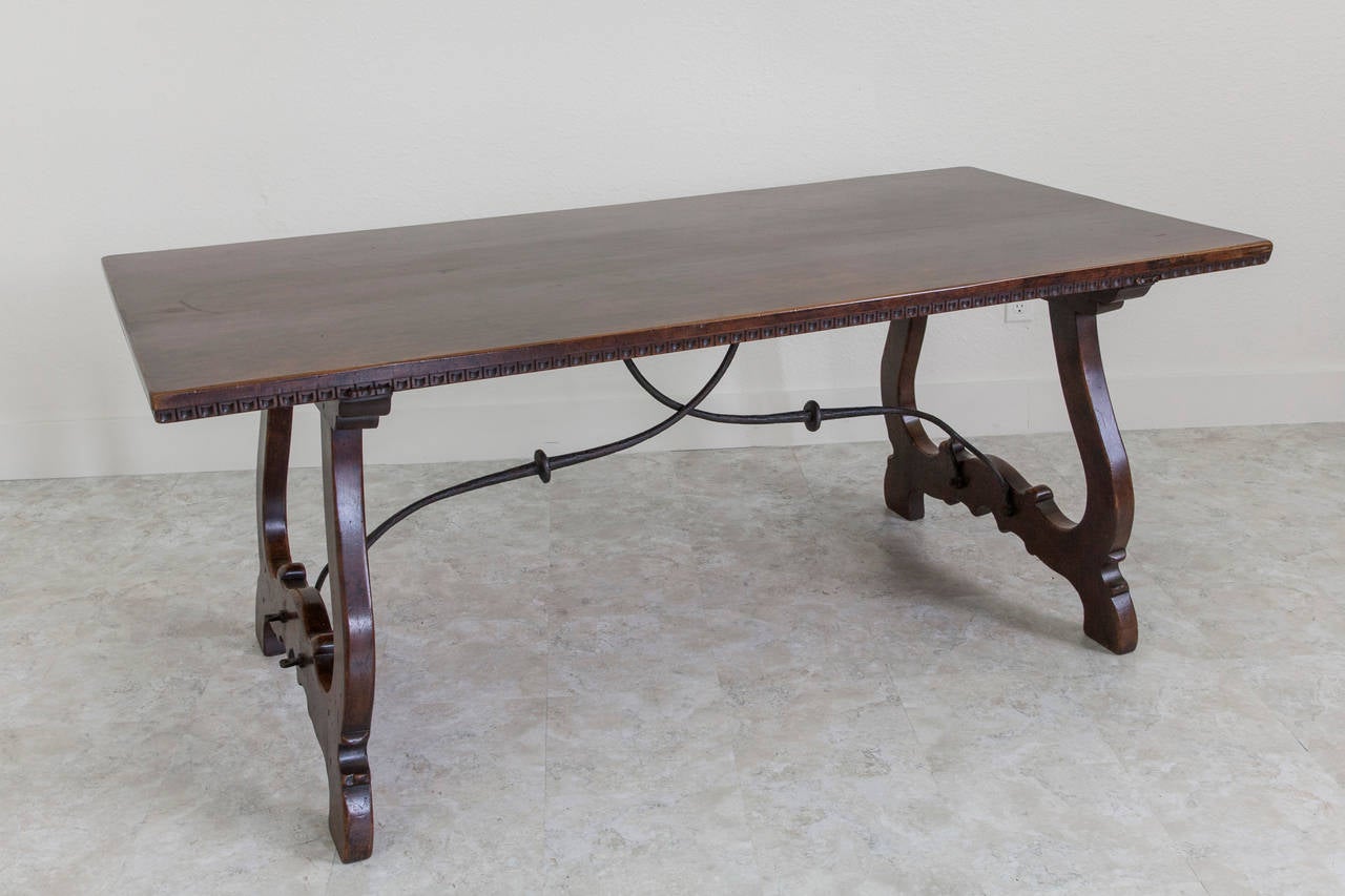 This impressive 19th century Spanish Renaissance style table features a hand-carved border as well as a hand-forged iron stretcher. The surface of this table has aged to a deep mahogany hue with a leather smooth feel. The scale of this table will