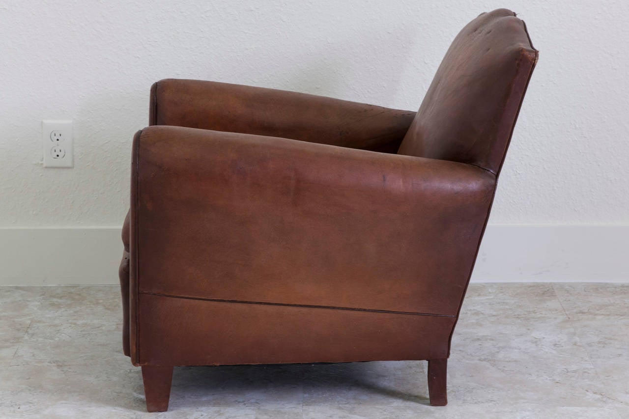 Superb pair of French Art Deco period moustache-back 1940s club chairs with all original leather. Comfortable and classic without being bulky. The beautifully aged leather combined with a unique smaller scale make this pair a great find.