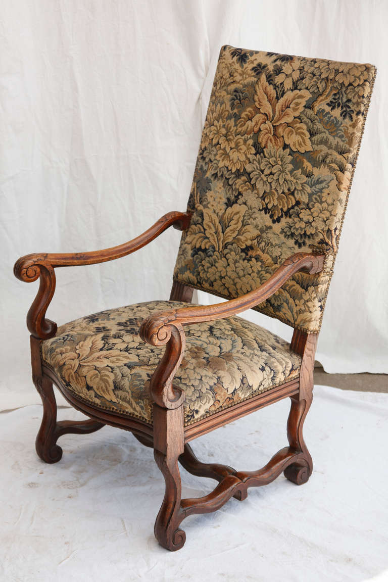 This grand scale hand carved oak Louis XIV style armchair features acanthus leaf detail and its original tapestry, c. 1880.  With brass nailhead trim, the tapestry is in beautifully preserved condition.