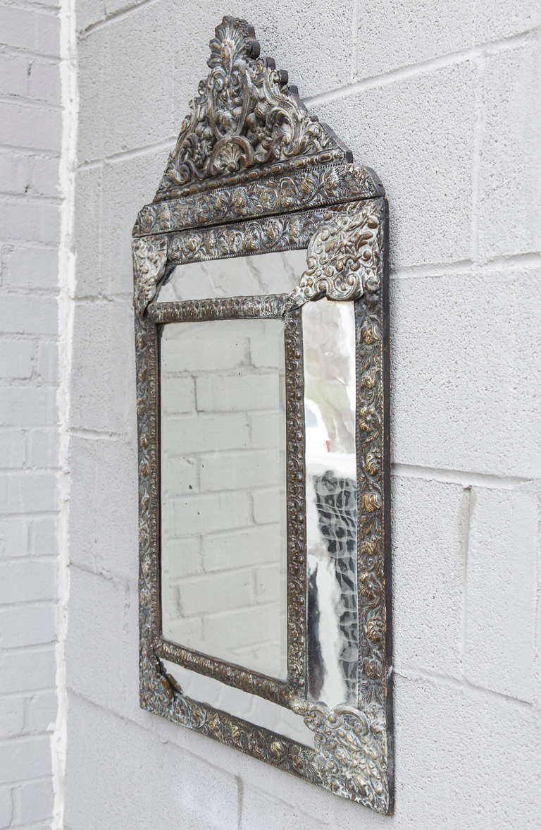 This richly detailed Napoleon III bronze repoussé mirror has a beautifully patinated finish on its floral motif double frame.  The original aged mirror insets on this piece lend additional warmth, while the central beveled piece of mirror remains