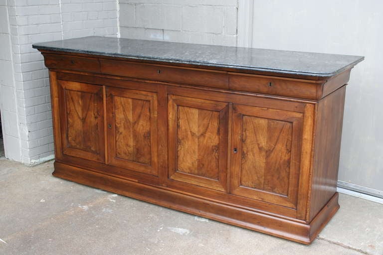 Book matched walnut Louis Philippe enfilade with beveled soapstone top, c. 1830-1848.  Single compartment behind each pair of doors. One large central drawer and two side drawers.