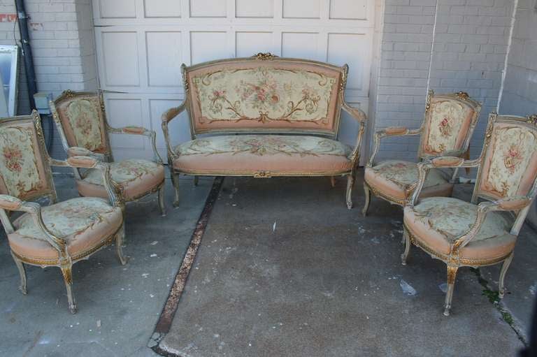 FIVE PIECE Louis XV-Louis XVI Transition style hand carved gilt  salon set. Settee and four fauteuils, each with foliate-carved frame and padded back, seat, and armrests, are upholstered in Aubusson tapestry depicting flowers and musical