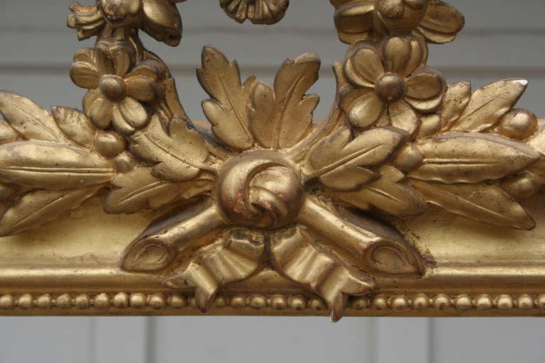 Pair of nineteenth century Louis XVI style gold leafed wood and plaster cornices with floral wreaths, holly leaves, and berries.