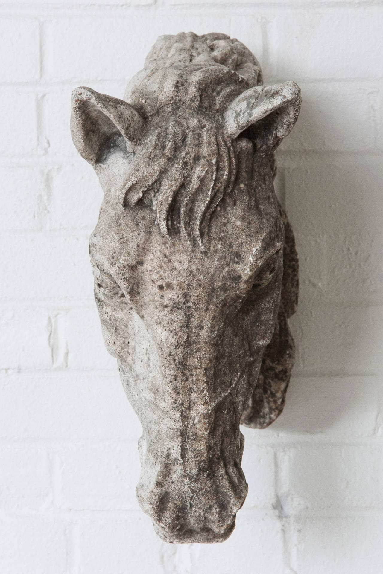 A perfect accent for any equestrian enthusiast, this cast limestone horse head is in large life-size scale with a beautiful patina from its years hanging in a private French stabile. This piece includes a heavy cable which runs through the body of