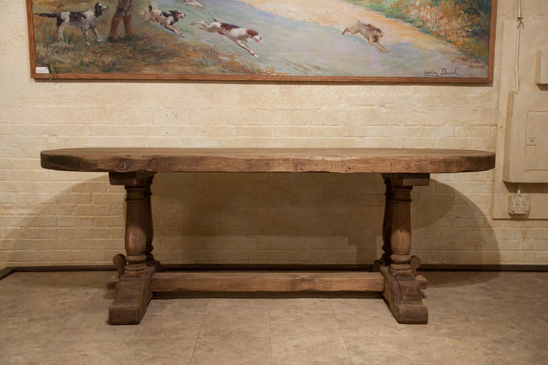 This artisan made hand hewn washed oak monastery table from Normandy, France features a rare oval three inch thick top.and double baluster legs.  C. 1930.
