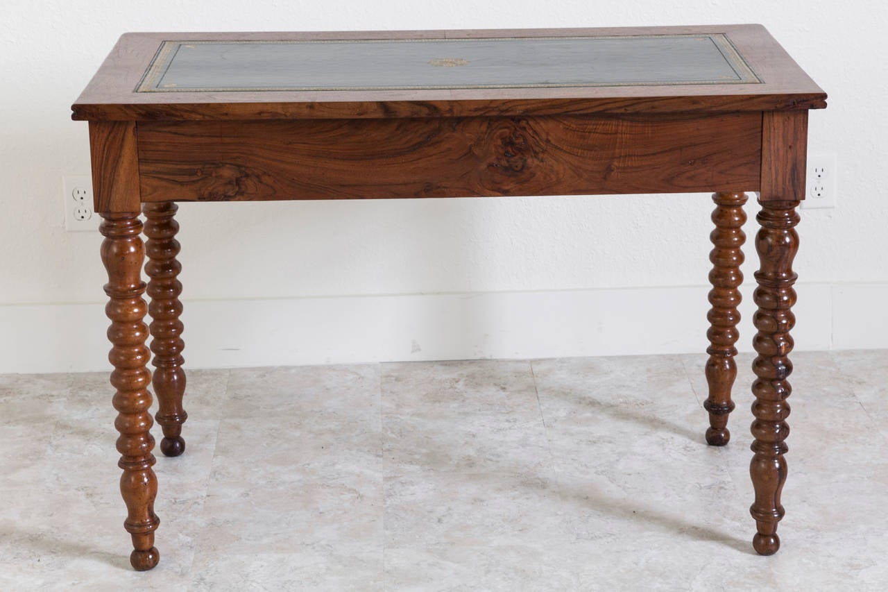 A rare find, this Louis Philippe desk is finished in beautifully burled bookmatched walnut. Raised on turned legs with ball feet, this elegant period piece has two drawers and a pristine gold tooled green leather top. An excellent scale for a small