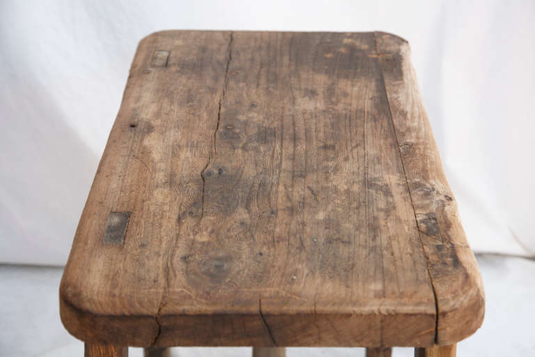 This nineteenth century artisan made hand hewn bench features mortis and tenon construction with wooden pegs and a single drawer.  It was originally used on a dairy farm in the Normandy region of France.