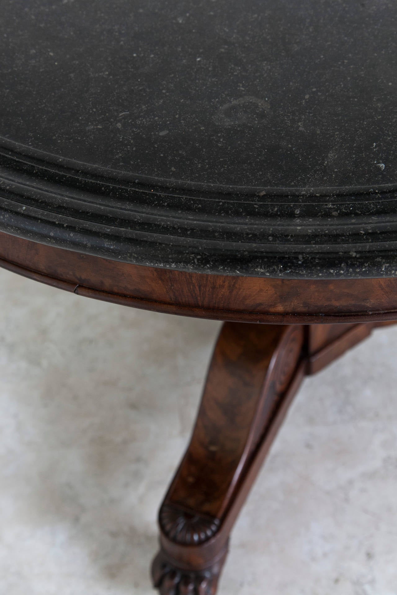 This Restauration period flamed mahogany center table rests on a tripod pedestal with claw's feet and casters. Its top is made of exceptional multibeveled Belgian black marble. This circa 1815 piece is of an ideal size as either a foyer table or to