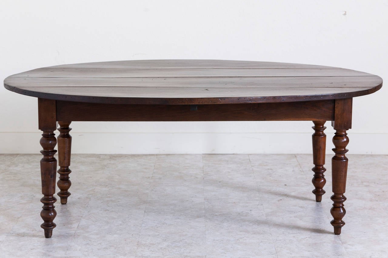 The deep hued walnut of this unusually large oval farm table contributes to its warm and welcoming presence. This piece is made entirely of solid walnut and is all hand pegged with beautifully turned thick legs and drop leaves. Easily seats eight