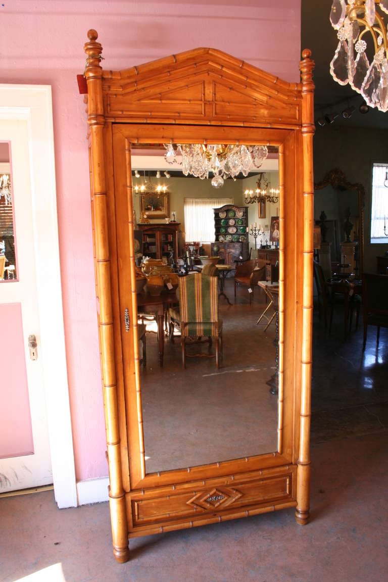 French colonial period pitch pine faux bamboo armoire with mirrored door, c. 1900. One exterior drawer and one interior drawer.  Interior shelf has hanging brass clothing rod.  Additional adjustable shelves may be added.