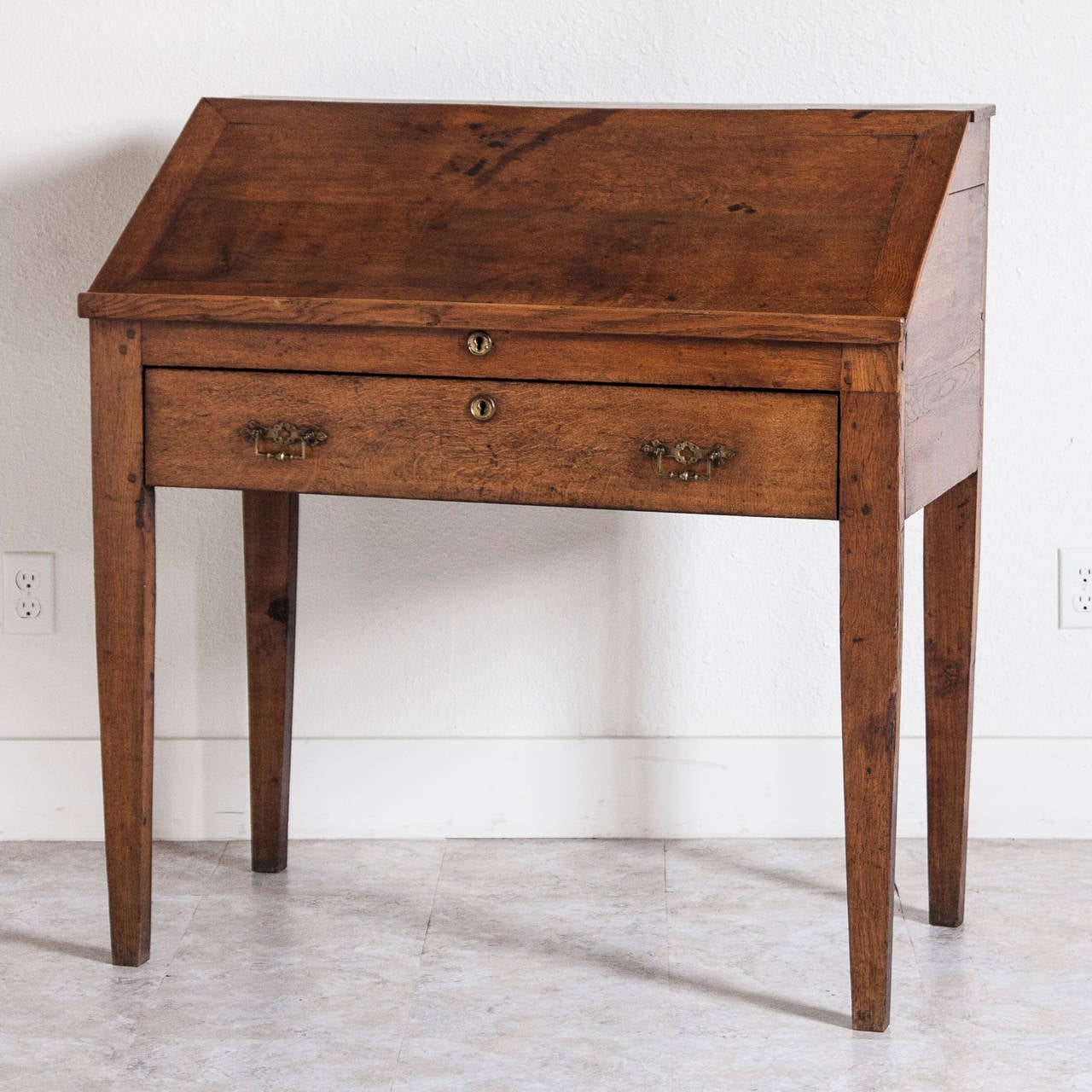 Simple construction, clean lines, and beautifully aged wood give this desk a wonderfully comfortable and warm feel. An excellent scale for narrow spaces while still having a great deal of work space for writing and drawing. This early 19th century