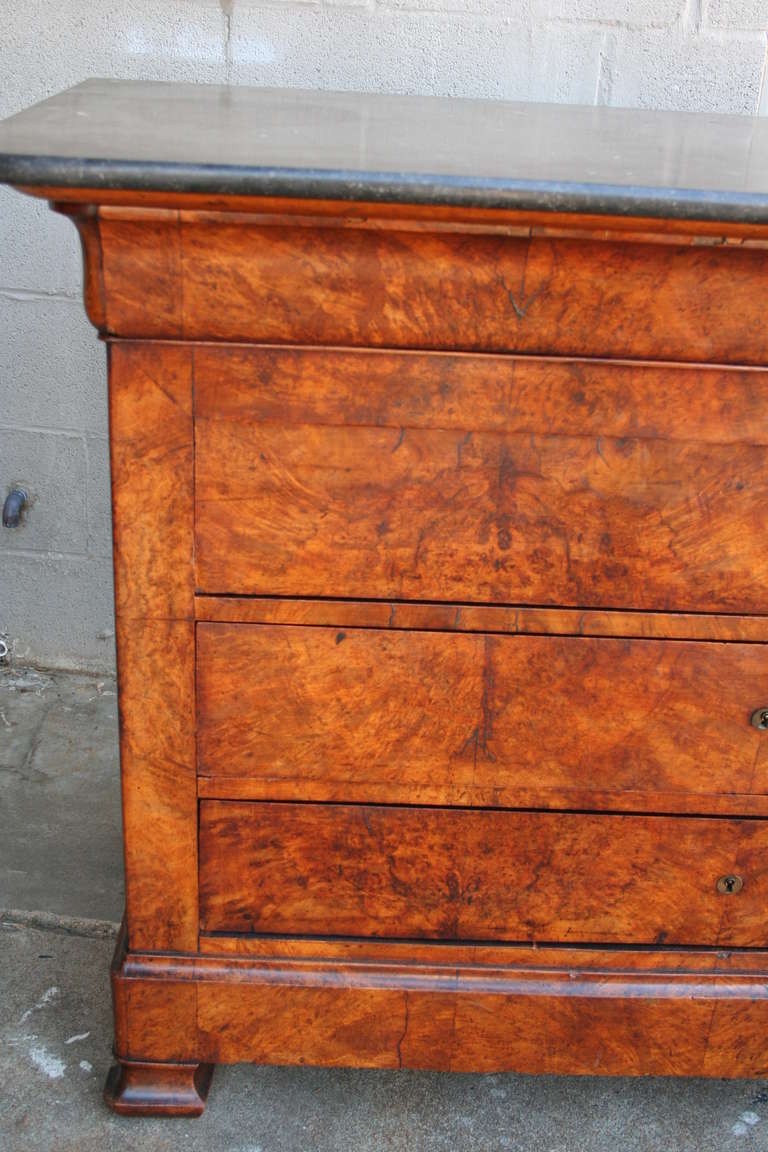 This classic burled walnut Louis Philippe chest  has four drawers and a black marble top.  A key is used to open each drawer, leaving a sleek surface which lets the beautiful burled wood shine. The smooth black marble top will blend with all decors.