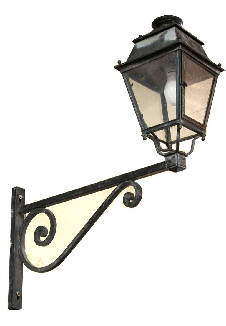 This large iron lantern is mounted on its original bracket, circa 1900. For exterior use, this old world piece will create a grand entrance.  Originally plumbed for gas, but converted to electricity.