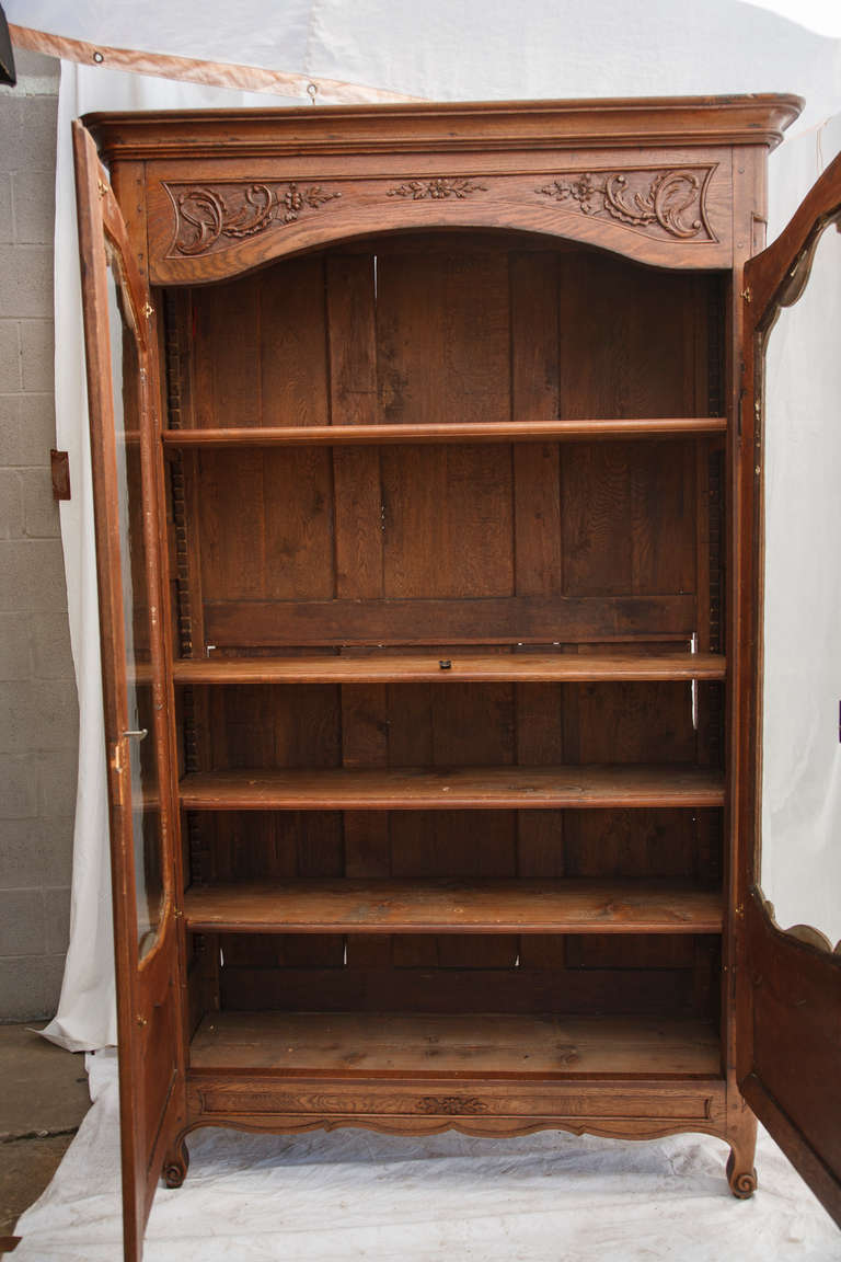 This elegantly hand carved oak Louis XV style vitrine will showcase your collectibles or books beautifully behind its original glass doors. With four adjustable shelves, a great amount of storage is available in this piece. Found in Normandy, circa