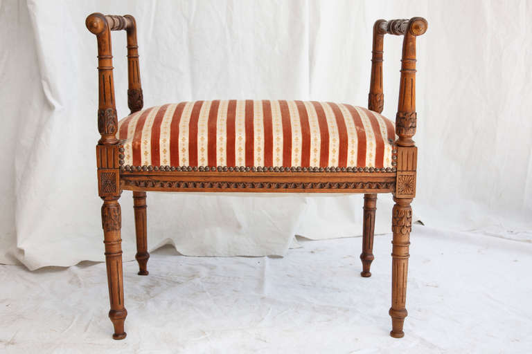 This hand carved walnut Louis XVI style banquette features fluted legs leading directly into high turned armrests.  The vintage upholstery is in excellent condition. c. 1890.