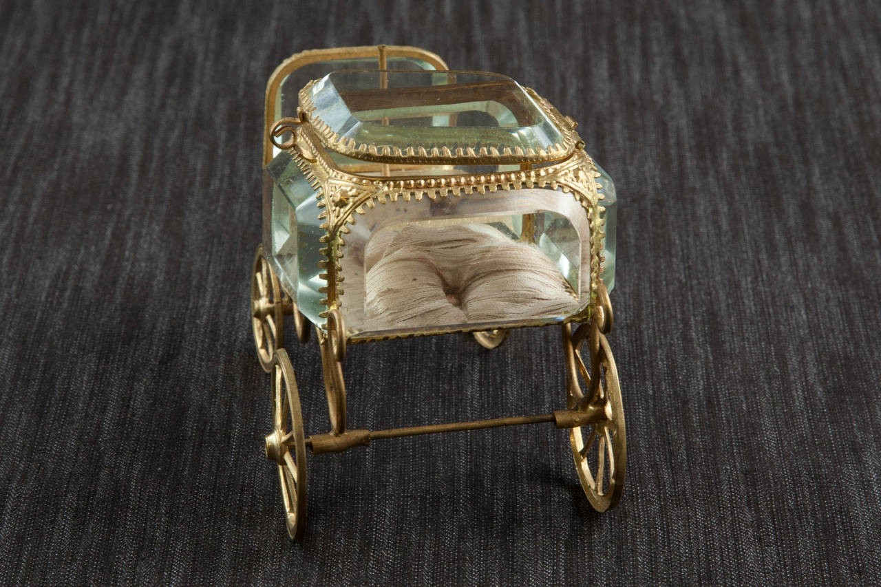 This delightful little chariot made of gilt bronze feature deep beveled glass and a silk pillowed interior. Originally designed to hold a pocket watch for display at one's bedside, this rare find would make an incredible display piece for a vanity