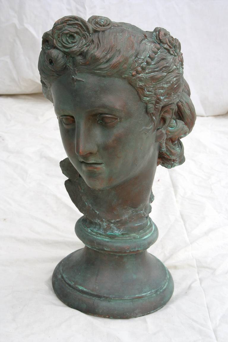 French Art Nouveau patinated plaster bust of an elegantly coiffed young woman, circa 1900. Base measures 7.5 inches in diameter.