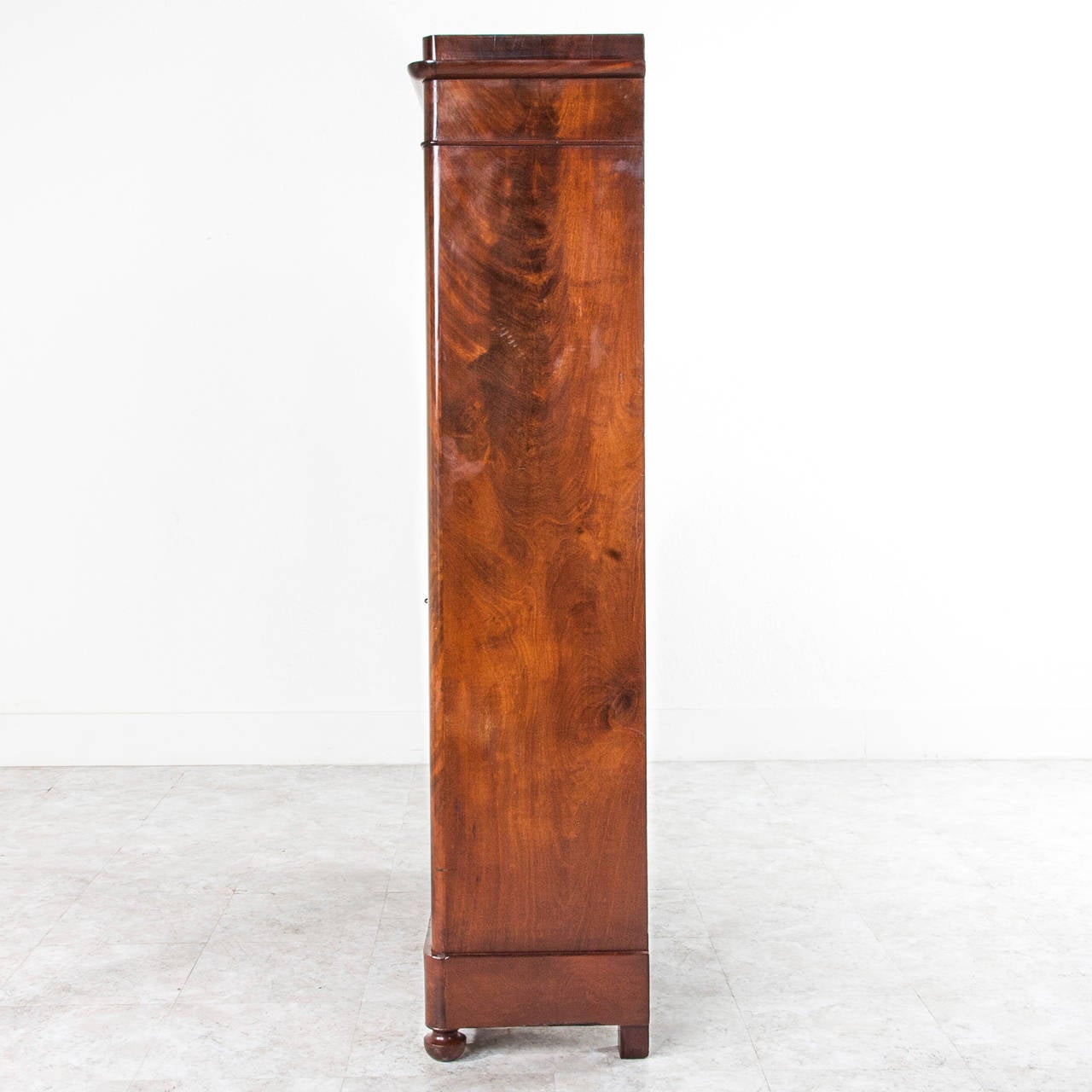 This period Louis Philippe bibliotheque is finished in French polished flamed mahogany. The classic simple Louis Philippe lines allow the beauty of the wood to speak for this piece, while the original hand blown glass doors will give anything